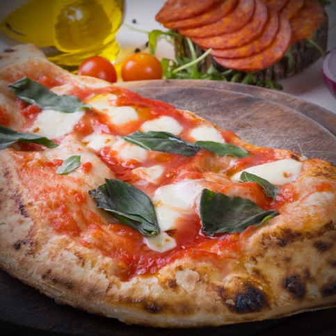 Close up view of a Margherita Neapolitan style pizza with buffalo mozzarella, tomato sauce and basil. Landscape format.