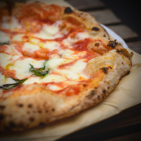 Close up view of a Margherita Neapolitan style pizza with buffalo mozzarella, tomato sauce and basil. Landscape format.